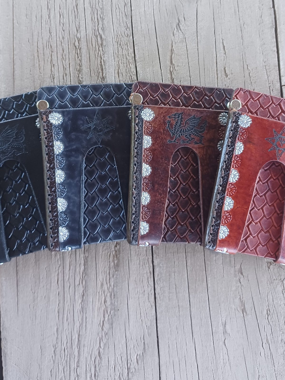 Four hand-tooled leather money-clip wallets in black, green, chestnut and red